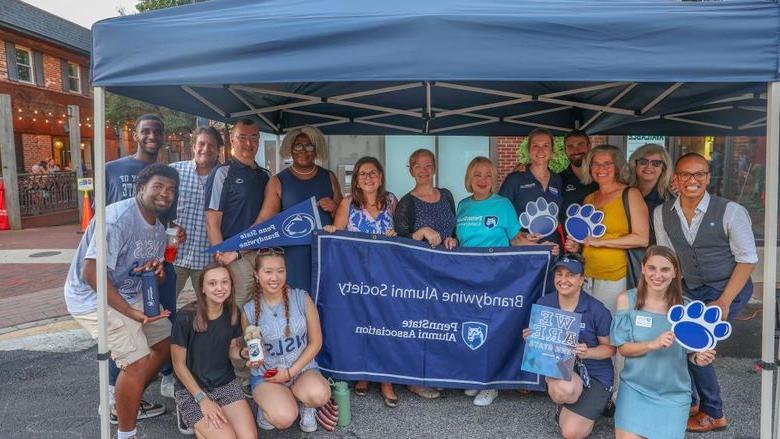 group of people at Dining Under the Stars holding Brandywine Alumni Society banner